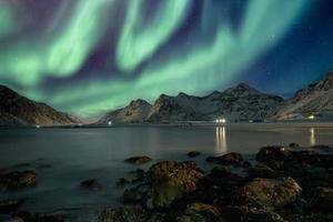 Aurora Borealis mit Sternen über Bergkette an der Küste