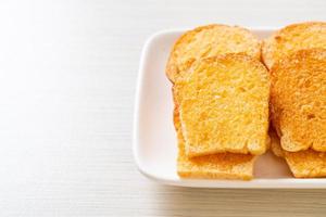 gebackenes knuspriges Brot mit Butter und Zucker auf Teller foto