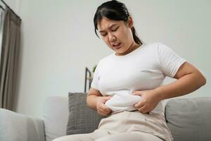 schließen oben von mollig Frau halten ihr Bauch Fett auf das Sofa. Diät Lebensstil zu reduzieren Bauch und gestalten oben gesund, Bauch Muskel Konzept. foto