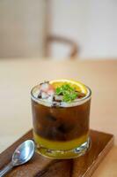 ein Glas von vereist Americano schwarz Kaffee und Schicht von Orange mit geschnitten Orange Obst foto