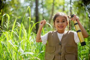 asiatisch wenig Mädchen erkunden Natur durch Vergrößerung Brille und Fernglas im das Park. Ausbildung, Feld Reisen, Forschung, und Entdeckung Konzepte. foto