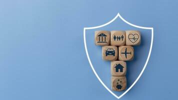Leben Versicherung Konzept mit hölzern Blöcke und Symbole von verschiedene Typen von Versicherung auf ein Blau Hintergrund. foto