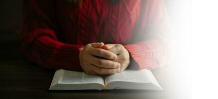 Hände zusammen im Gebet zu Gott zusammen mit der Bibel im christlichen Konzept und in der Religion, Frau betet in der Bibel auf dem Holztisch foto