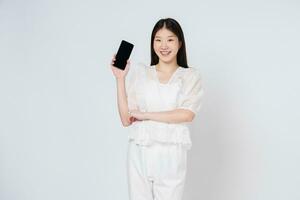 lächelnd asiatisch Frau halten Handy, Mobiltelefon Telefon während Stehen isoliert Über Weiß Hintergrund. foto