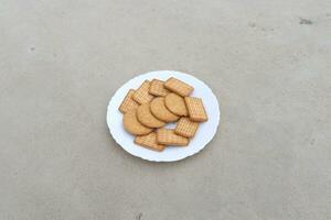 Kekse auf ein Weiß Teller auf das Boden. foto