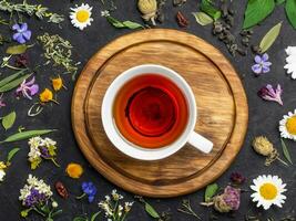 Tasse von Tee mit trocken Blätter und Blumen auf hölzern Hintergrund foto