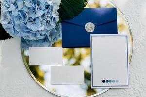 Hochzeitseinladung in einem grauen Umschlag auf einem Tisch mit grünen Zweigen foto