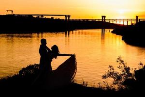 Silhouetten eines glücklichen jungen Paares und Mädchens auf einem Hintergrund von orangefarbenem Sonnenuntergang in der Sandwüste foto