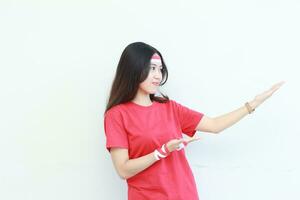 Porträt von schön asiatisch Frau tragen rot Outfit feiern Indonesien Unabhängigkeit Tag zeigen zu das Seite zum Kopieren Raum foto