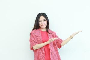 Porträt von schön asiatisch Frau tragen rot Outfit zeigen zu das Seite zum Kopieren Raum mit lächelnd Geste foto