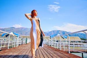 Frau auf dem Pier im langen Kleid foto
