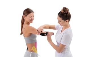 Physiotherapeut, der Kinesio-Tape auf den Arm der Patientin anwendet. Kinesiologie, Physiotherapie, Rehabilitationskonzept. Tennis- oder Golfer-Ellenbogenbehandlung. foto