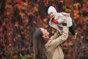 Bucht mit Mama im Herbstpark. Mutter und Tochter im Herbst. Mama hält das Baby im Arm. Mutter mit ihrer kleinen Tochter im Herbstpark bei einem Spaziergang. foto