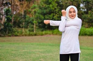 Junge muslimische Frau macht Muskeldehnung, bevor sie Yoga-Bewegungen macht foto