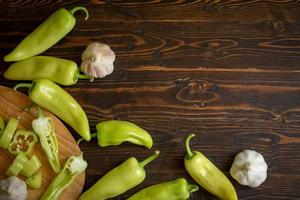 grüne scharfe Chilischoten und Chili in Scheiben geschnitten mit Knoblauch auf Holzuntergrund foto