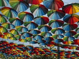 bunte Regenschirme draußen als Dekor. Regenschirme in verschiedenen Farben gegen den Himmel und die Sonne foto