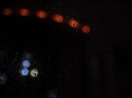 Regentropfen auf Glas und helle Lichter im Hintergrund der Nacht. Regentropfen Nacht Bokeh foto
