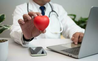 ein Arzt halten und zeigen ein rot Herz beim Krankenhaus Büro. medizinisch Gesundheit Pflege und Arzt Mitarbeiter Bedienung Konzept. foto