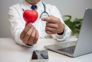 ein Arzt zeigen ein rot Herz beim Krankenhaus Büro. medizinisch Gesundheit Pflege und Arzt Mitarbeiter Bedienung Konzept. foto