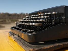 Vintage-Schreibmaschine auf einem Holztisch, handgefertigt auf blauem Himmelshintergrund