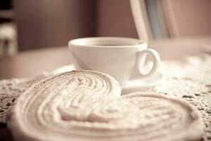 Weiß Tasse von schwarz Kaffee und ein Süss butterartig Plätzchen auf das Tabelle foto