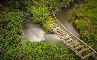 kleine ländliche Fußgängerbrücke über einen gewundenen Bach foto