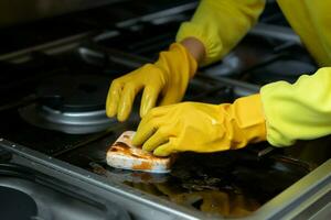 oben Nieder Aussicht Frauen behandschuhte Hand Peelings Herd, finden Freude im Post Kochen Reinigung ai generiert foto