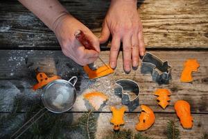 Frauenhände und weihnachtliche dekorative Figuren aus Orangenschale auf dem alten Holztisch. foto