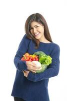 schön asiatisch Frau ein hell, gesund Lächeln hält ein Glas Schüssel von organisch Gemüse. gesund Essen Konzept. Weiß Hintergrund foto
