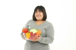Fett asiatisch Frau halten ein Schüssel von frisch organisch Gemüse Essen zum gut Gesundheit. das Konzept von verlieren Gewicht, reduzieren Fett gesund Essen, Ernährung, Rezept Lebensmittel. Weiß Hintergrund foto