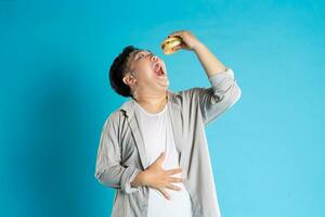 Porträt von asiatisch Mann Essen schnell Essen auf Blau Hintergrund foto