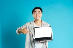 Bild von asiatisch Mann mit Laptop auf Blau Hintergrund foto