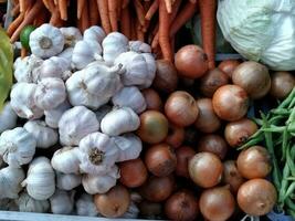 Foto von mehrere Typen von Gemüse zum Kochen Zutaten im ein Weiß Korb. unter diese Gemüse sind Möhren, Kohl, Knoblauch, Zwiebeln, Möhren, Chayote