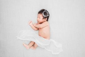 Neugeborenes Baby schläft und trägt eine silberne Krone foto