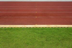 Textur von Laufen Rennstrecke rot Gummi Rennstrecken im draussen Stadion sind 8 Spur und Grün Gras Feld, leer Leichtathletik Stadion mit Leichtathletik, Fußball Feld, Fußball Feld. foto