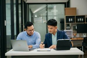 zwei asiatisch Geschäftsmann diskutieren Investition Projekt Arbeiten und Planung Strategie mit Tablette Laptop Computer im modern Büro. foto