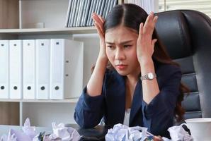 Asiatische Geschäftsfrau, die mit Stress im Büro sitzt Frauen sind bei der Arbeit nicht glücklich foto