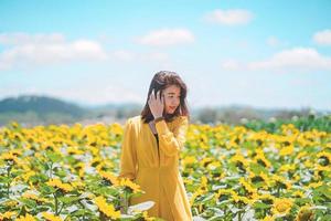 asiatische Frau fröhlich mit schönem Sonnenblumenfeld, Sommerreisekonzept