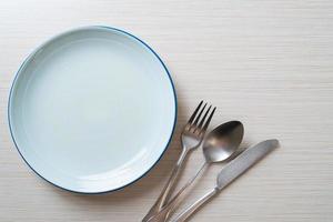 leerer Teller oder Teller mit Messer, Gabel und Löffel auf Holzfliesenhintergrund foto