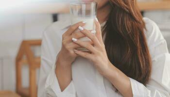 Porträt von ein zufrieden jung asiatisch Frau Trinken Milch von das Glas isoliert Über Weiß Hintergrund foto