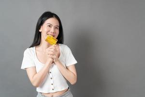 asiatische Frau mit glücklichem Gesicht und präsentiert Kreditkarte in der Hand zeigt Vertrauen und Zuversicht für die Zahlung foto