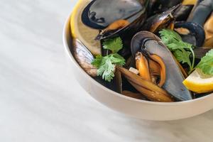 Muscheln mit Kräutern in einer Schüssel mit Zitrone foto