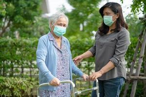 Asiatische Seniorin oder ältere alte Dame, die eine Gesichtsmaske trägt, die im Park neu ist, um die Sicherheitsinfektion des Covid-19-Coronavirus zu schützen. foto