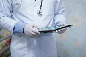 Arzt, der ein digitales Tablet hält, um Daten für die Behandlung von Patienten in der Krankenstation zu suchen