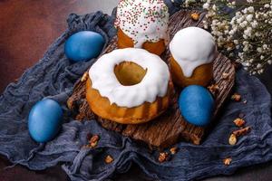 festliche Kuchen mit weißer Glasur, Nüssen und Rosinen mit Ostereiern auf dem festlichen Tisch foto