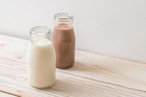 Schokoladenmilch und frische Milch in der Flasche auf Holzhintergrund foto
