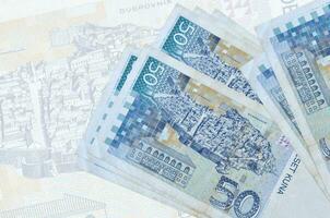 50 kroatische Kuna-Scheine liegen im Stapel auf dem Hintergrund einer großen halbtransparenten Banknote. abstrakte Darstellung der Landeswährung foto