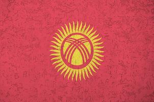 kirgisische flagge in hellen farben auf alter reliefputzwand dargestellt. strukturierte Fahne auf rauem Hintergrund foto