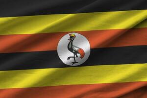 Uganda-Flagge mit großen Falten, die im Innenbereich unter dem Studiolicht wehen. die offiziellen symbole und farben im banner foto