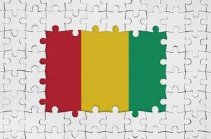 Guinea Flagge im Rahmen von Weiß Puzzle Stücke mit fehlt zentral Teil foto